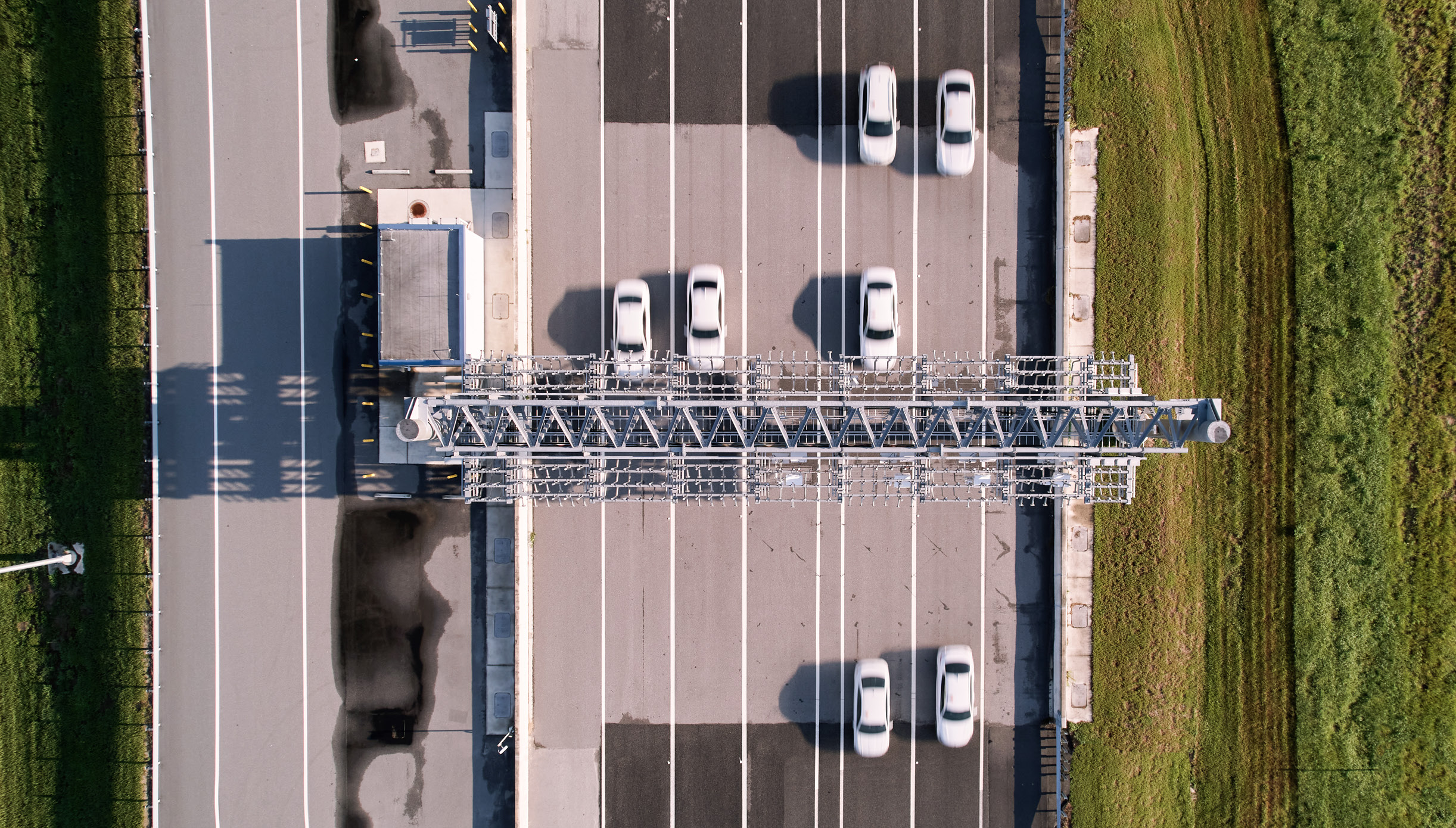 Aerial view of seven cars driving through one of the toll gantries on the high-speed oval