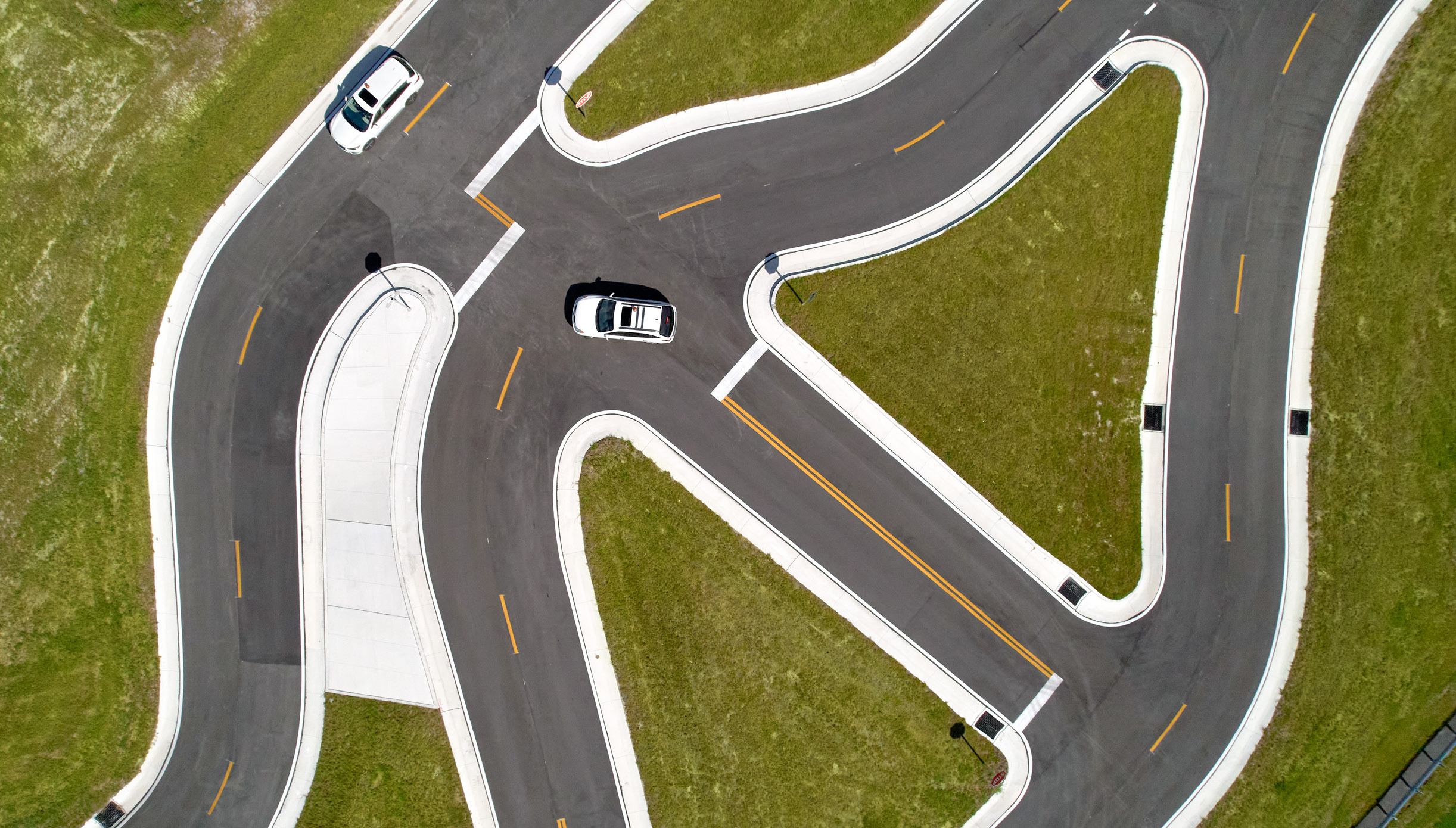 Overhead, aerial view of two white cars driving on the geometry track