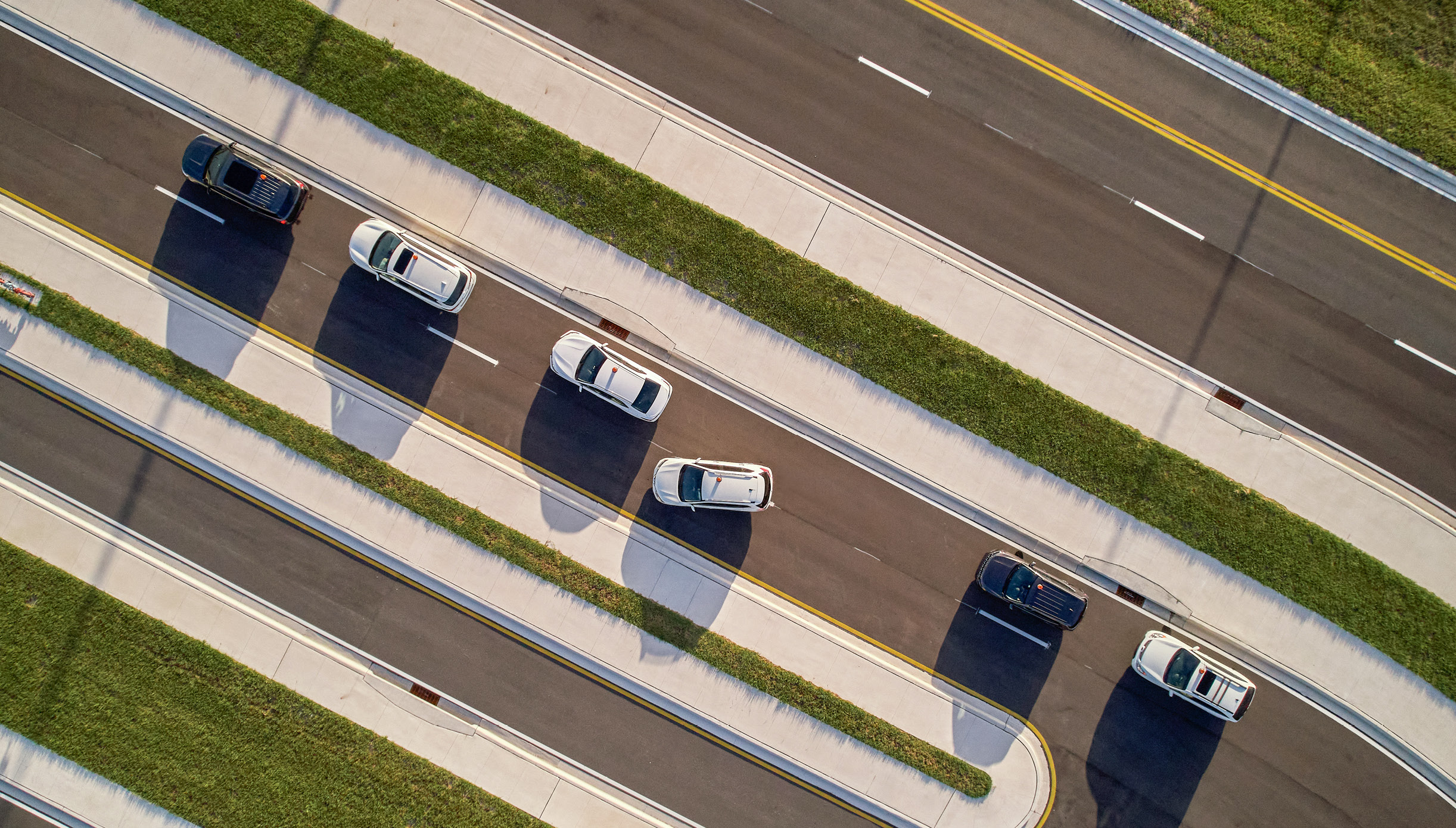 Overhead view of a vehicle merging out, leaving a line of parked cars in the Pick-Up/Drop-Off sector