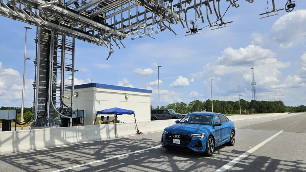 A test vehicle equipped with Indra’s advanced systems moves through a gantry positioned along the secured Oval Track at SunTrax, demonstrating the integration of cutting-edge technology within a controlled environment.