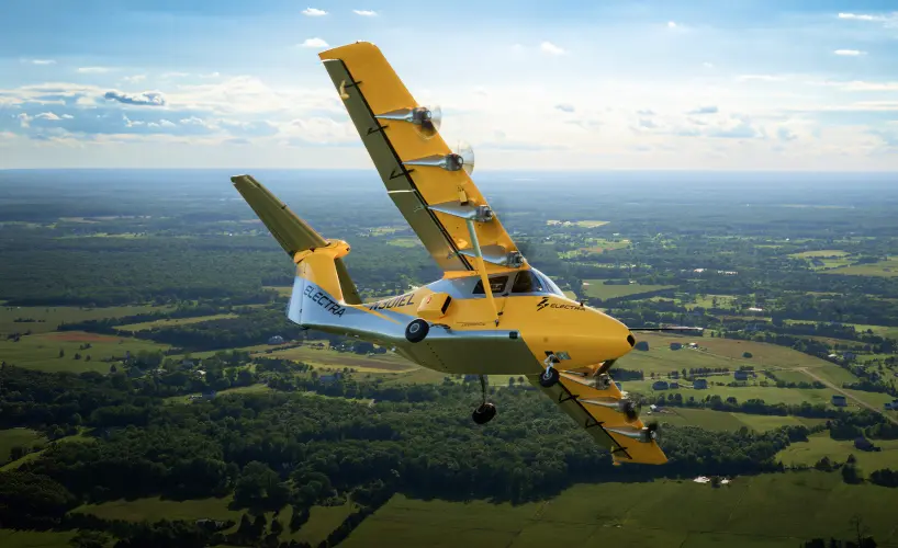 Distributed electric propulsion research aircraft flying over rural landscape